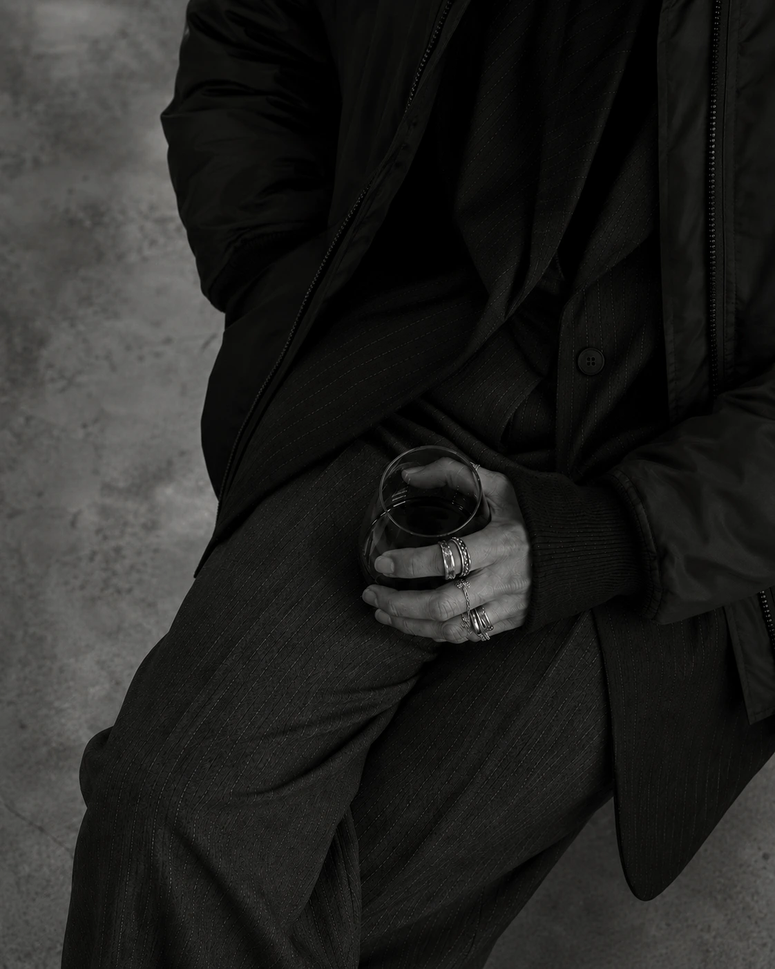Editorial — satin and bomber nylon, a held glass, in monochrome